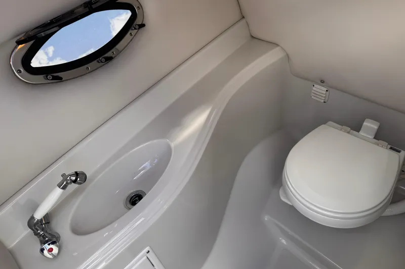 Slide: The Image of 2008 Crownline 320 LS boat bathroom with sink, toilet, and porthole window. - 27