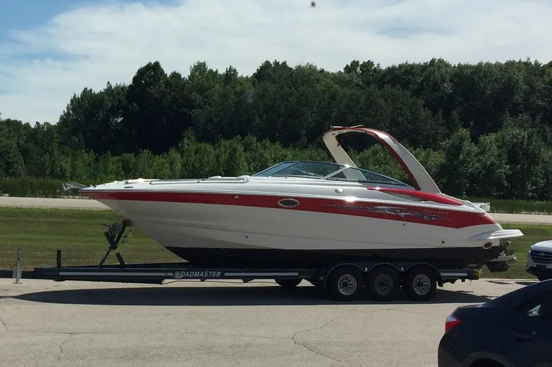 Slide: The Image of 2008 Crownline 320 LS boat on trailer, parked outdoors with trees in the background. - 8