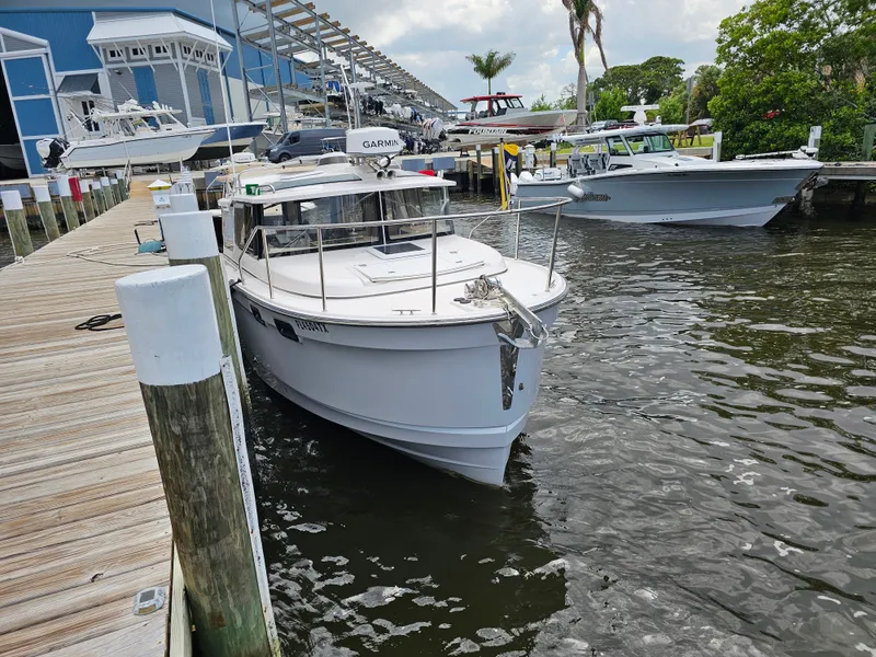 Slide: The Image of A white 2025 Ranger Tugs R-27 boat docked at a wooden pier in a marina. - 9
