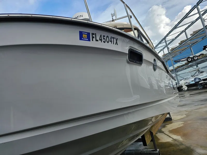 Slide: The Image of A 2025 Ranger Tugs R-27 boat is on a dry dock. It features a white exterior hull. - 39