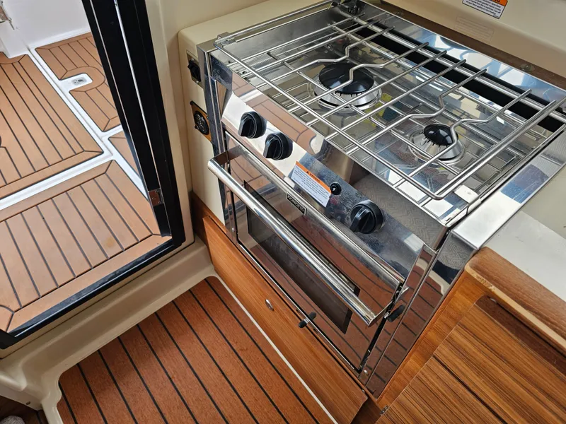 Slide: The Image of Interior of a Ranger Tugs R-27 featuring a stainless steel stove and wooden flooring. - 29