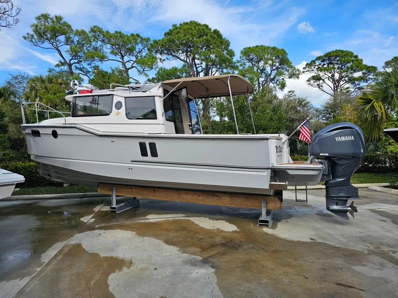 Slide: The Image of A Ranger Tugs R-27 boat is on a dry dock, surrounded by trees and blue sky. - 37