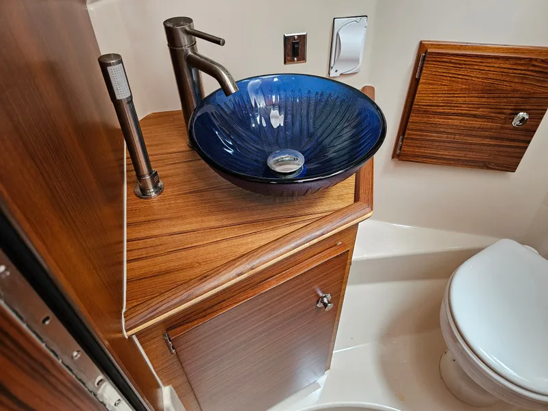 Slide: The Image of The image shows a stylish bathroom with a blue glass sink and wooden cabinetry. - 22