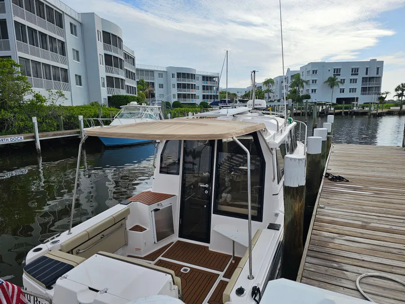 Slide: The Image of A 2025 Ranger Tugs R-27 docked. It features a sunshade and modern amenities. - 5