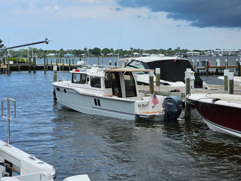 Slide: The Image of A 2025 Ranger Tugs R-27 is docked. It features a modern design with an American flag at the stern. - 8