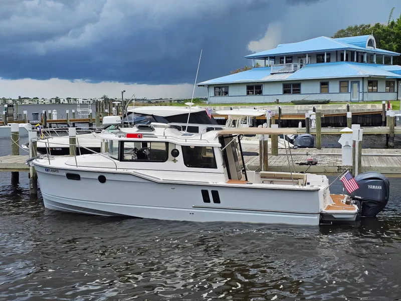 Slide: The Image of A 2025 Ranger Tugs R-27 is docked. The sky is cloudy. - 6