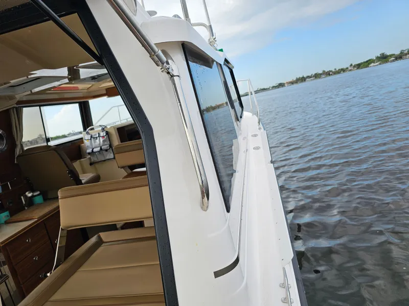 Slide: The Image of The image shows the side of a Ranger Tugs R-27 boat on the water. Interior seating is visible. - 36