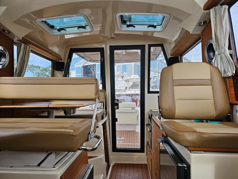 Slide: The Image of Interior of a 2025 Ranger Tugs R-27 with beige seating and wood accents. - 25