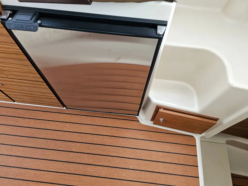 Slide: The Image of The interior view shows a refrigerator and wood paneling on a boat. - 27