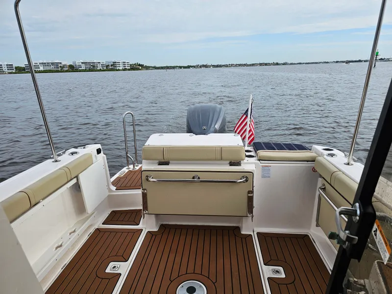 Slide: The Image of The deck of a 2025 Ranger Tugs R-27 with wood flooring and bench seating at the stern. - 33