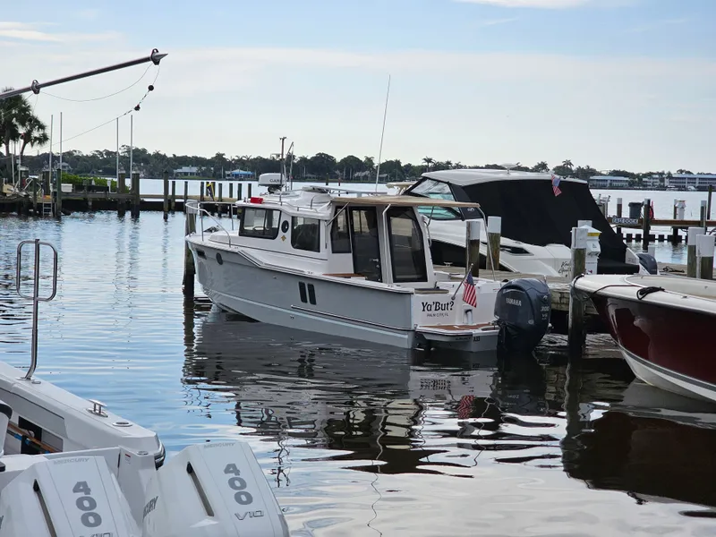 Slide: The Image of A 2025 Ranger Tugs R-27 is docked in a calm marina. Other boats are nearby. - 3