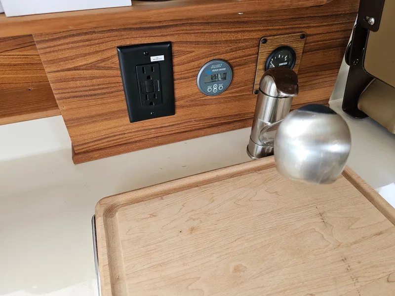 Slide: The Image of The galley of a 2025 Ranger Tugs R-27 features a wooden board, outlets, and a water faucet. - 30