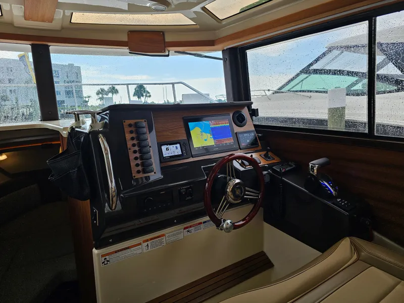 Slide: The Image of The cockpit of the 2025 Ranger Tugs R-27 features a modern navigation system and sleek steering wheel. - 13