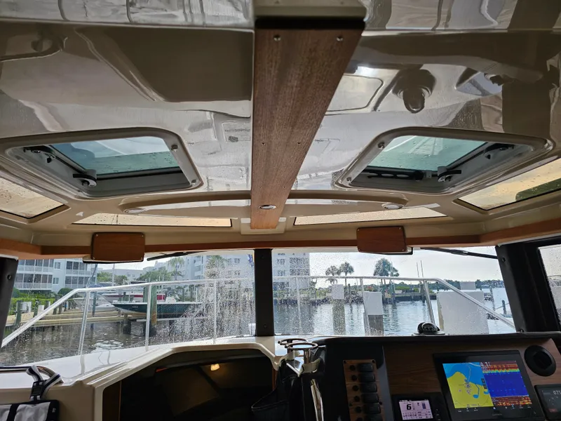 Slide: The Image of Interior view of a 2025 Ranger Tugs R-27 with large windows and a navigation system. - 14