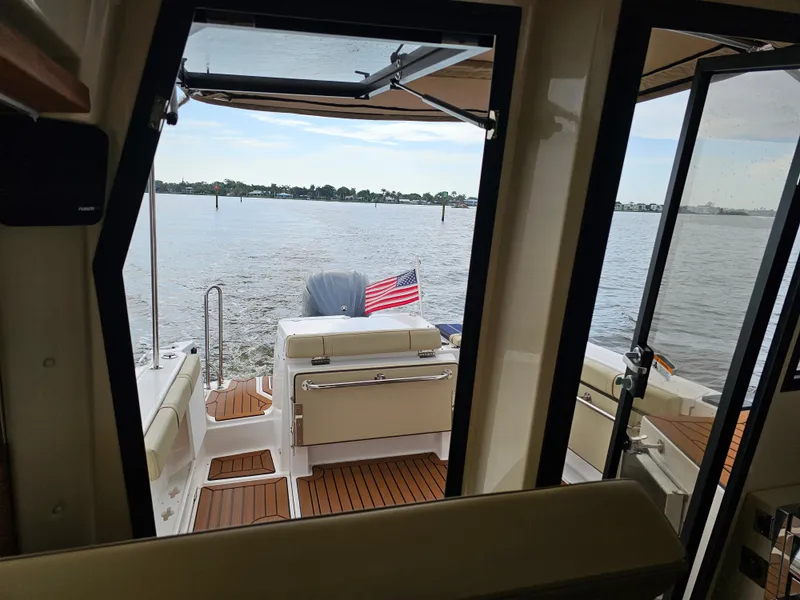 Slide: The Image of View from inside a Ranger Tugs R-27 looking out to the water. An American flag is visible. - 32