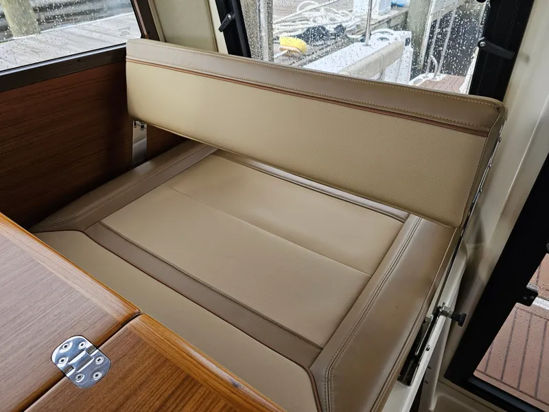 Slide: The Image of The interior of a 2025 Ranger Tugs R-27 features a beige leather bench seat next to a wooden table. - 28