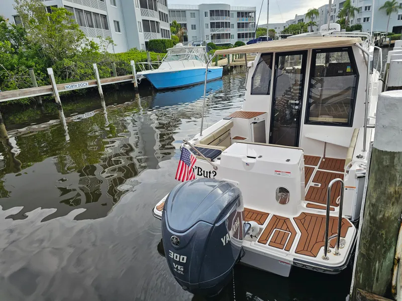 Slide: The Image of A 2025 Ranger Tugs R-27 is docked in a calm area. The outboard motor is visible. - 4
