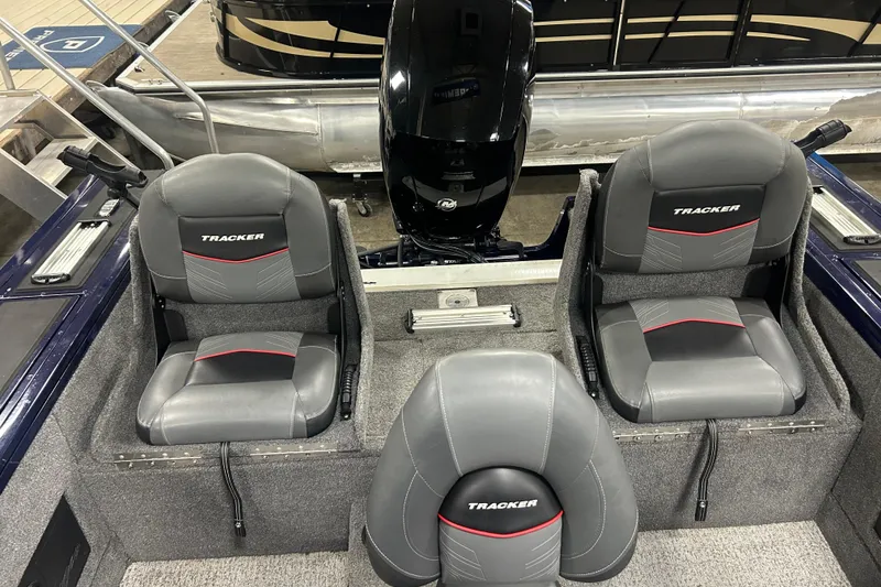 Slide: The Image of 2024 Tracker Targa V-18 Combo boat interior with three gray seats and motor. - 14
