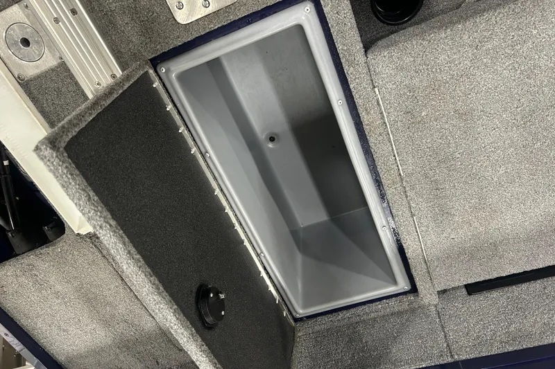 Slide: The Image of 2024 Tracker Targa V-18 Combo boat storage compartment with gray carpeted interior. - 20