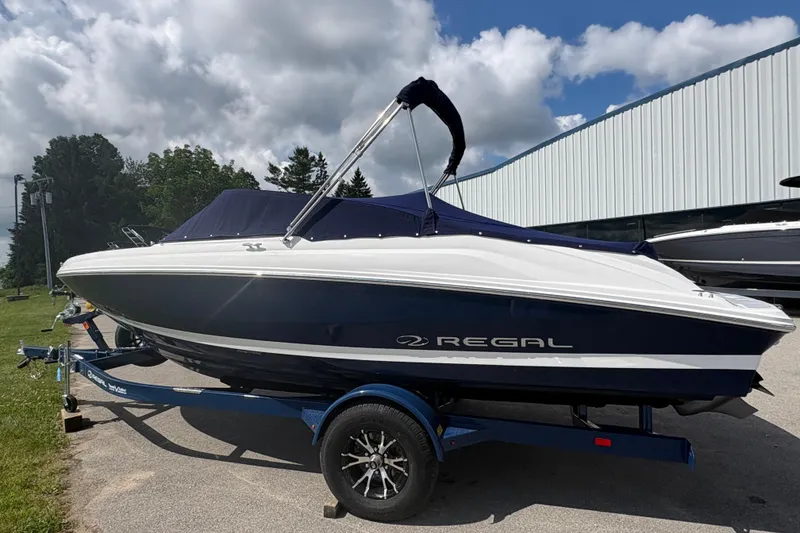 Slide: The Image of 2027 Regal 2000 ES boat on trailer, parked outdoors under cloudy sky. - 2