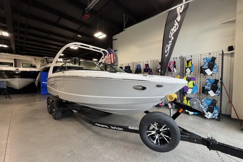 Slide: The Image of 2027 Regal LS2 boat on trailer in showroom, surrounded by colorful life jackets. - 2