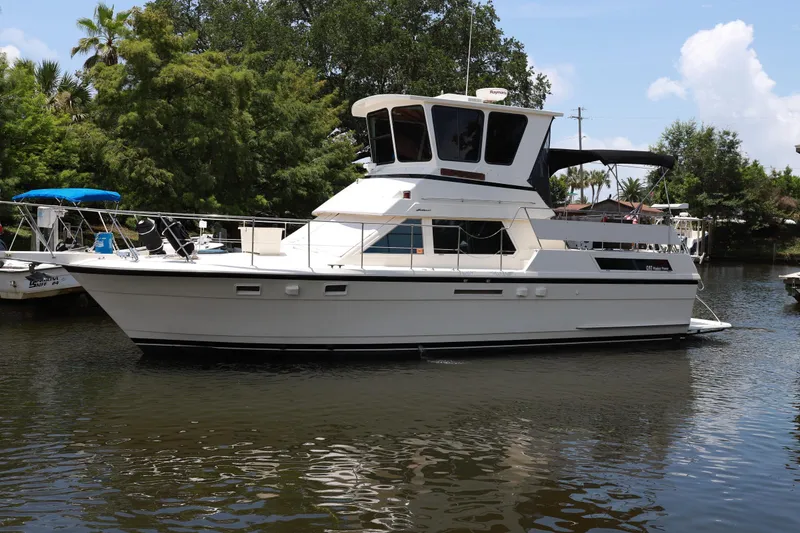 Slide: The Image of 1987 Hatteras 40 Double Cabin yacht on calm water, surrounded by lush greenery. - 6