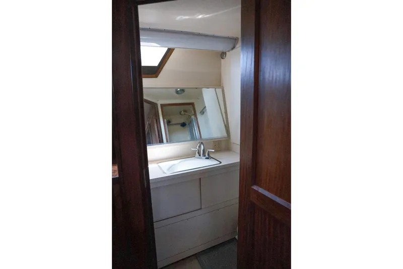 Slide: The Image of 1987 Hatteras 40 Double Cabin bathroom with sink, mirror, and wooden door. - 49