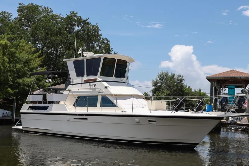 Slide: The Image of 1987 Hatteras 40 Double Cabin yacht docked on a sunny day, surrounded by trees and water. - 4