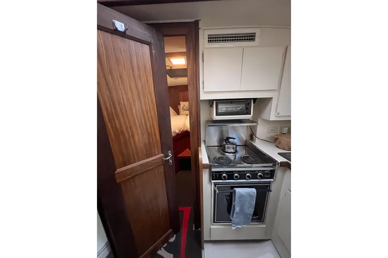 Slide: The Image of 1987 Hatteras 40 Double Cabin kitchen with stove, kettle, and wooden cabinetry. - 33