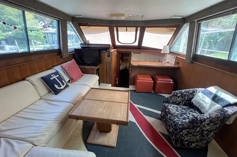 Slide: The Image of 1987 Hatteras 40 Double Cabin interior with cozy seating, nautical decor, and large windows. - 47
