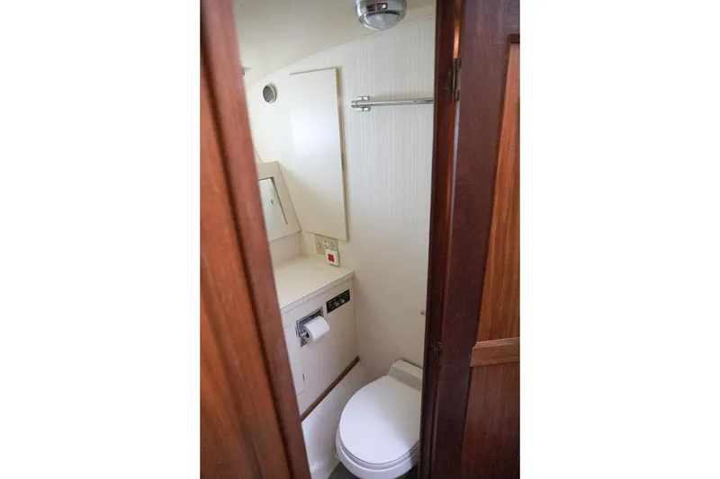 Slide: The Image of 1987 Hatteras 40 Double Cabin bathroom with toilet, mirror, and wooden door. - 51