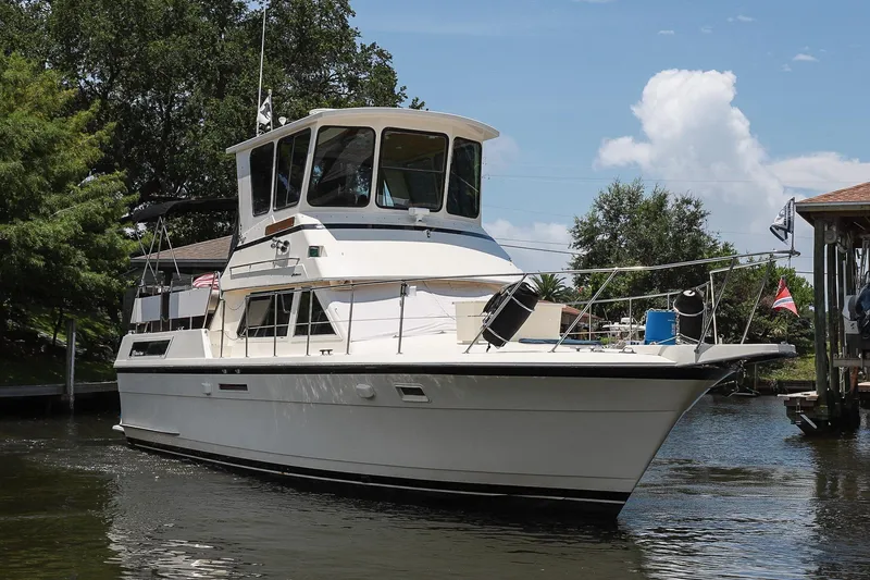 Slide: The Image of 1987 Hatteras 40 Double Cabin yacht on a serene waterway, surrounded by lush greenery. - 5