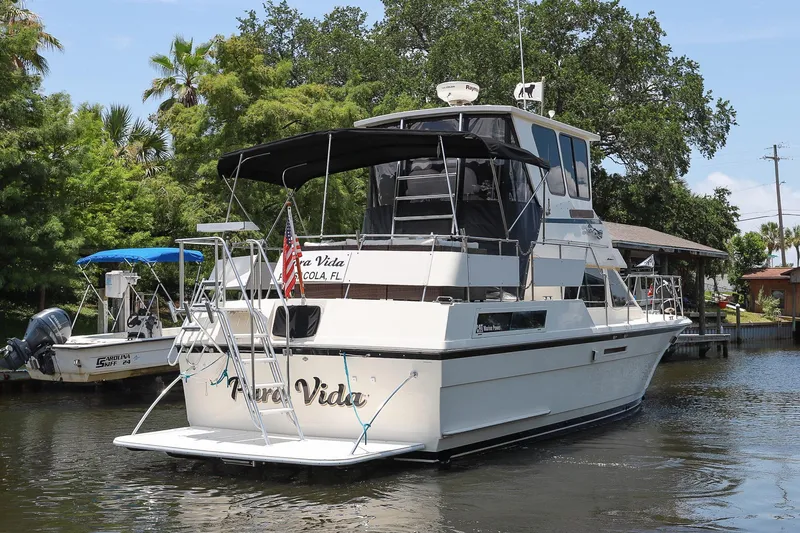 Slide: The Image of 1987 Hatteras 40 Double Cabin yacht docked on a serene waterway. - 8