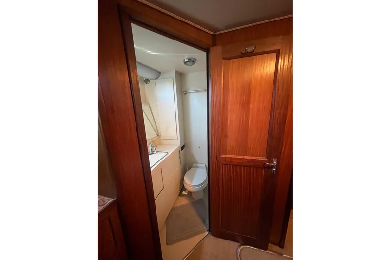Slide: The Image of Bathroom interior of 1987 Hatteras 40 Double Cabin yacht, featuring wood paneling and compact design. - 24