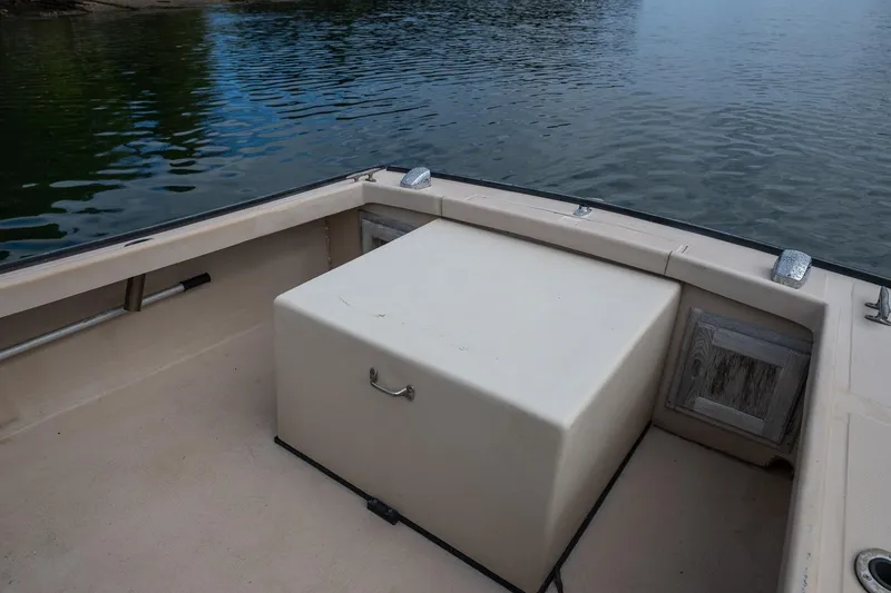 Slide: The Image of 1989 Ellis 24 Open boat interior with storage compartment, docked on calm water. - 38