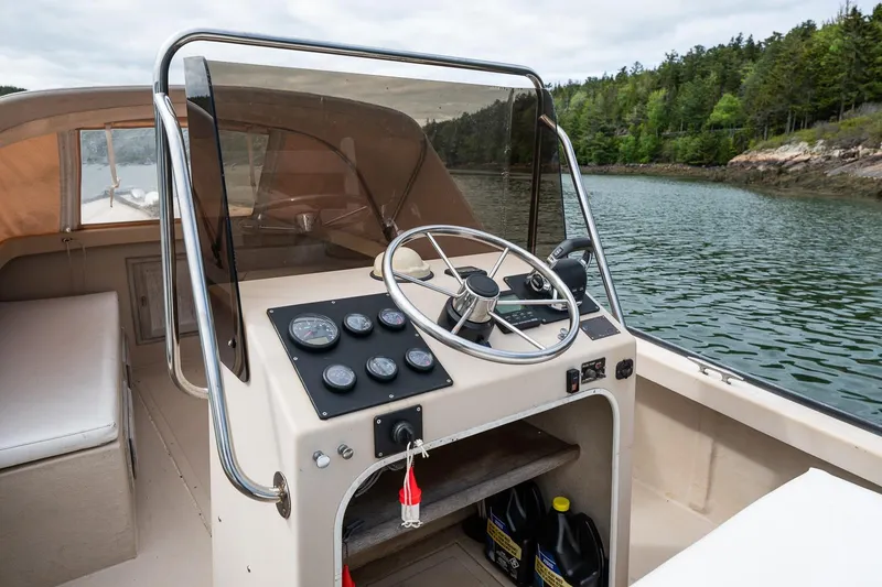 Slide: The Image of 1989 Ellis 24 Open boat cockpit with steering wheel, gauges, and scenic water view. - 25