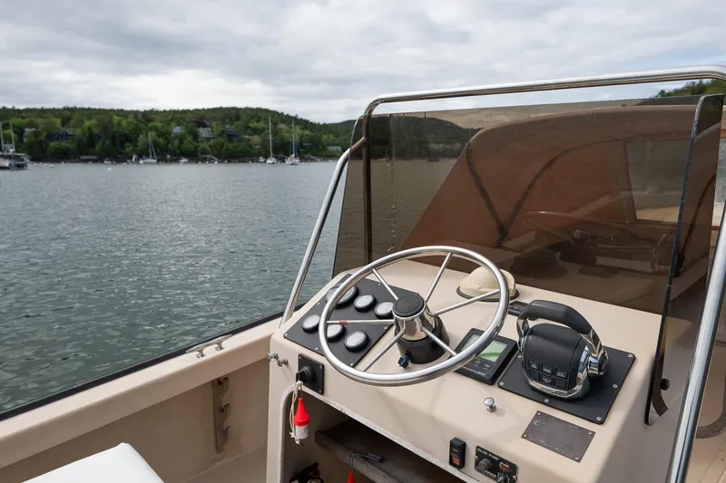 Slide: The Image of 1989 Ellis 24 Open boat dashboard with steering wheel, controls, and scenic lake view. - 27