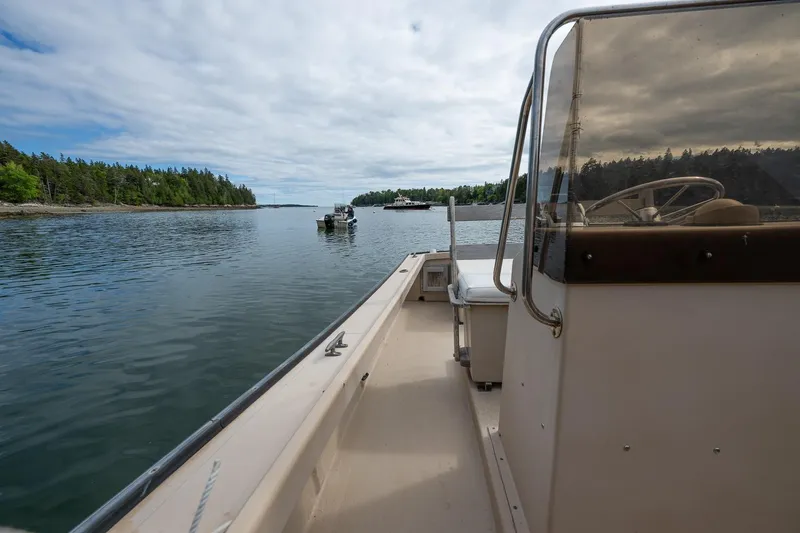 Slide: The Image of 1989 Ellis 24 Open boat cruising on a calm lake with forested shoreline. - 34