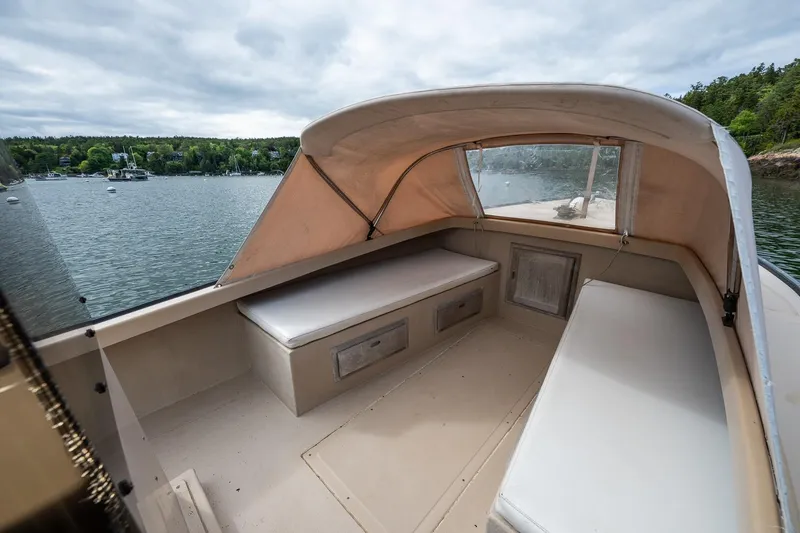 Slide: The Image of 1989 Ellis 24 Open boat interior with cushioned seating, docked on a scenic lake. - 28