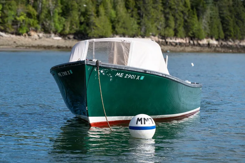 Slide: The Image of 1989 Ellis 24 Open boat moored on calm water with forested shoreline background. - 2