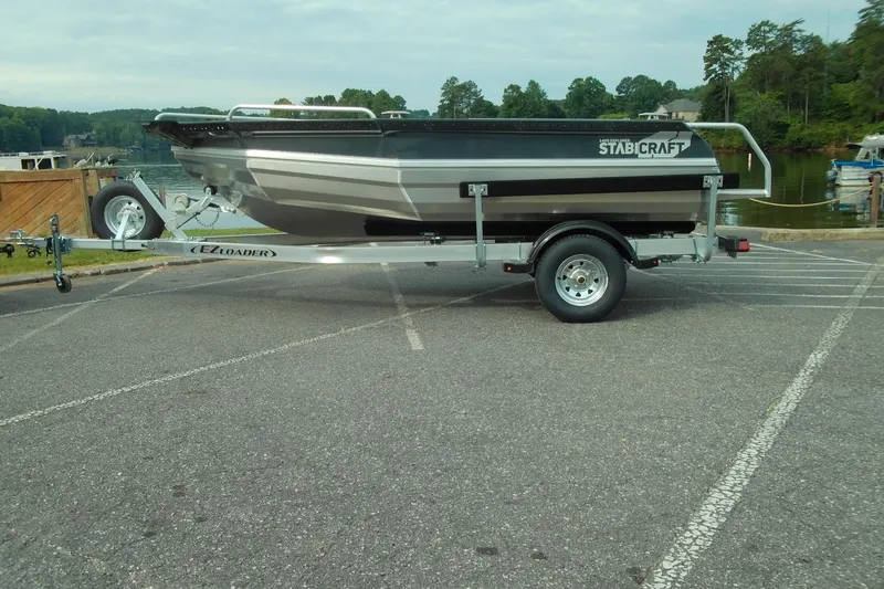 The Image of 2026 Stabicraft 1450 Explorer boat on trailer, parked near a scenic lake. - 1