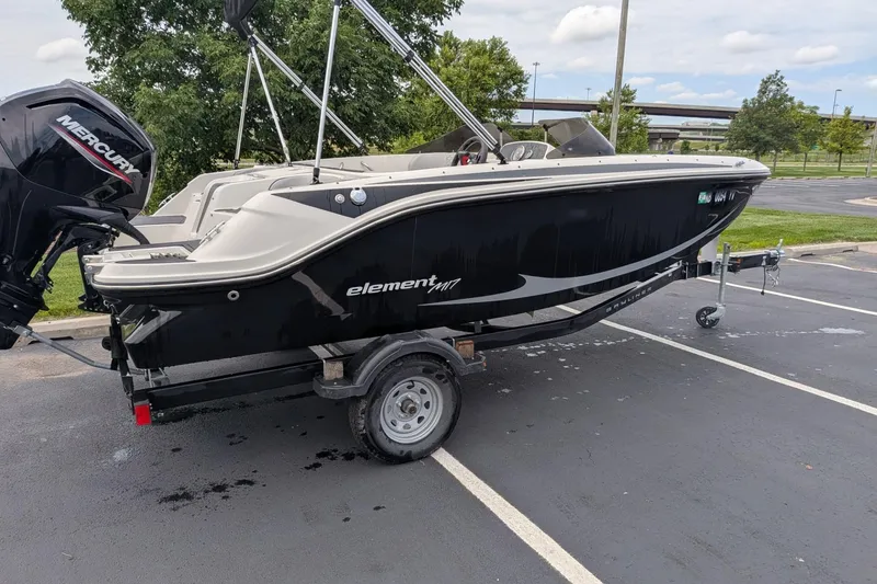 Slide: The Image of 2023 Bayliner Element M17 boat on trailer in parking lot. - 2
