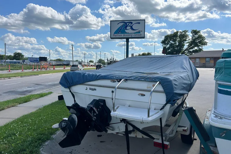 Slide: The Image of 1999 Bayliner 1954 Capri boat covered, parked near Premier Boating Center sign. - 11