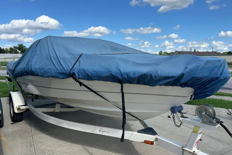 Slide: The Image of 1999 Bayliner 1954 Capri boat covered with blue tarp on trailer, parked outdoors. - 13