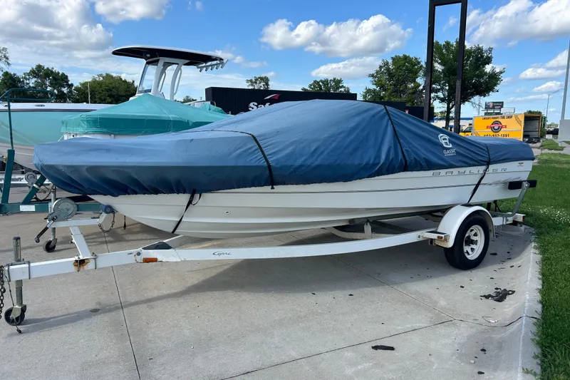 Slide: The Image of 1999 Bayliner 1954 Capri boat on trailer, covered with blue tarp, parked outdoors. - 12