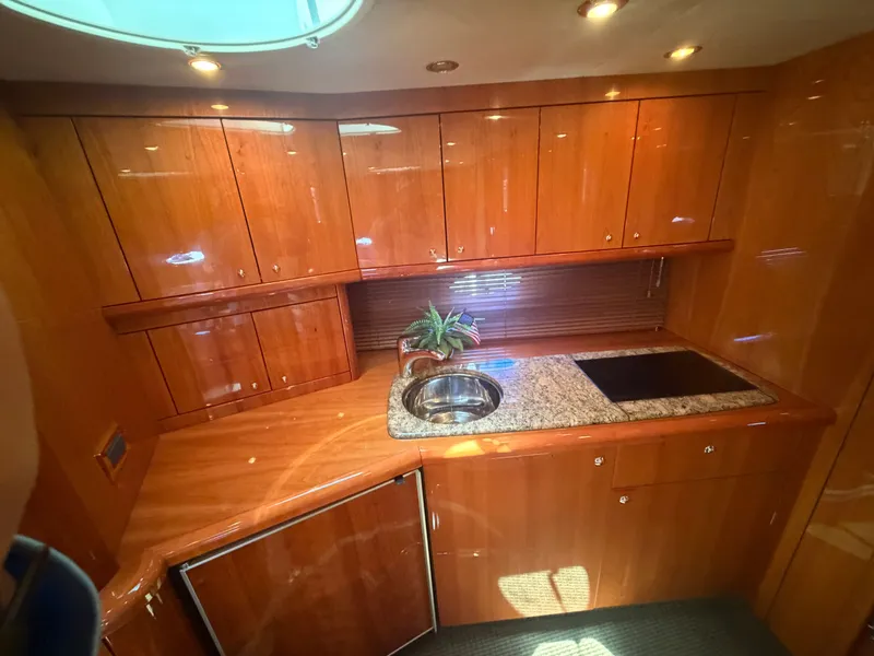 Slide: The Image of The 2008 Sunseeker Portofino 53 kitchen features glossy wood cabinets, a sink, and a stove. - 20