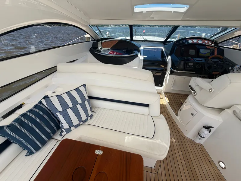 Slide: The Image of Interior of a Sunseeker Portofino 53 with white seating and wooden table, overlooking the water. - 8