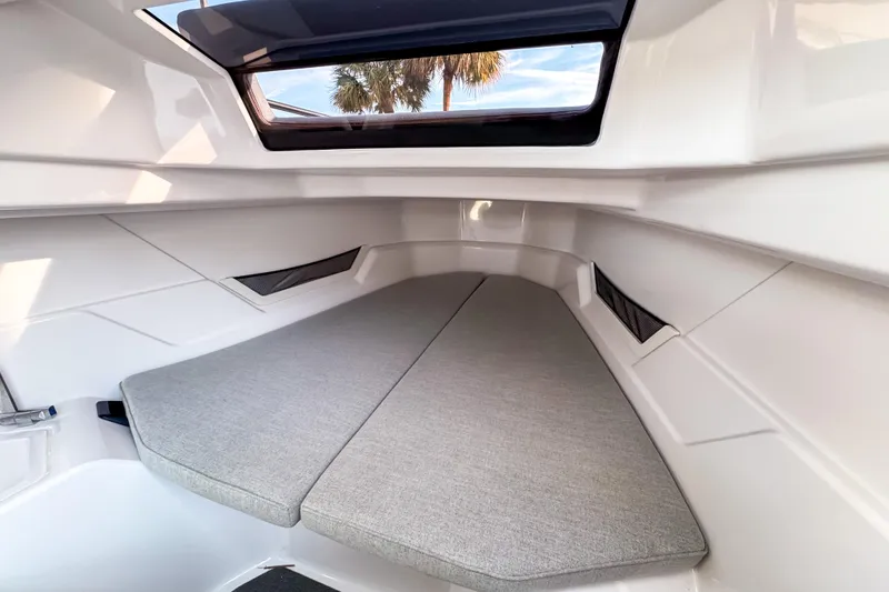 Slide: The Image of 2023 Axopar 25 Cross Top cabin interior with cushioned seating and window view. - 16