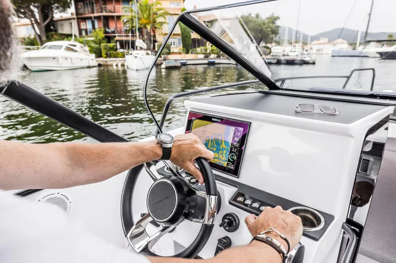 Slide: The Image of A person steers an Axopar 25 Cross Top boat on calm waters. - 14