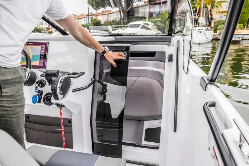 Slide: The Image of A man opens the cabin door of an Axopar 25 Cross Top boat in a marina. - 17